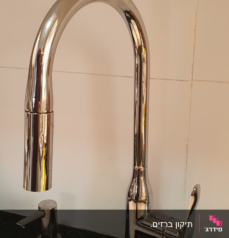 ברז נירוסטה מבריק על כיור מטבח שחור